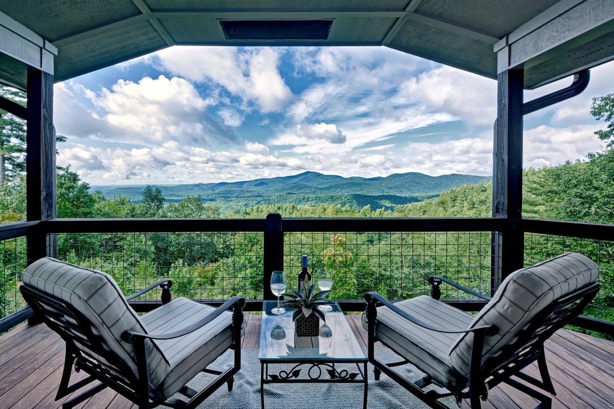 A comfortable seating arrangement faces a sweeping mountain view, with a coffee table arranged for drinks or conversation. The mood is calm and inviting, perfect for socializing or savoring the natural grandeur surrounding the home.