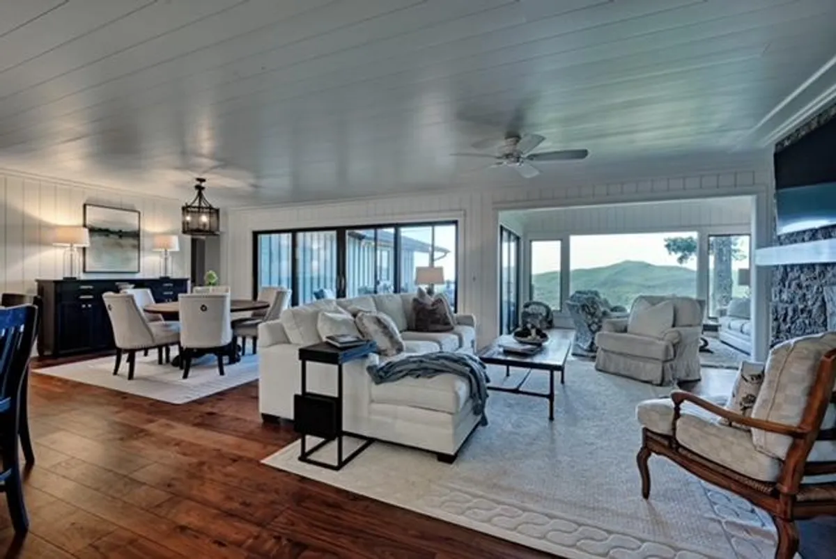 A cozy, inviting living and dining space with large windows that frame natural light. Comfortable seating and an elegant dining table offer a welcoming spot to relax after outdoor adventures, while the windows suggest a strong connection to the surrounding scenery.